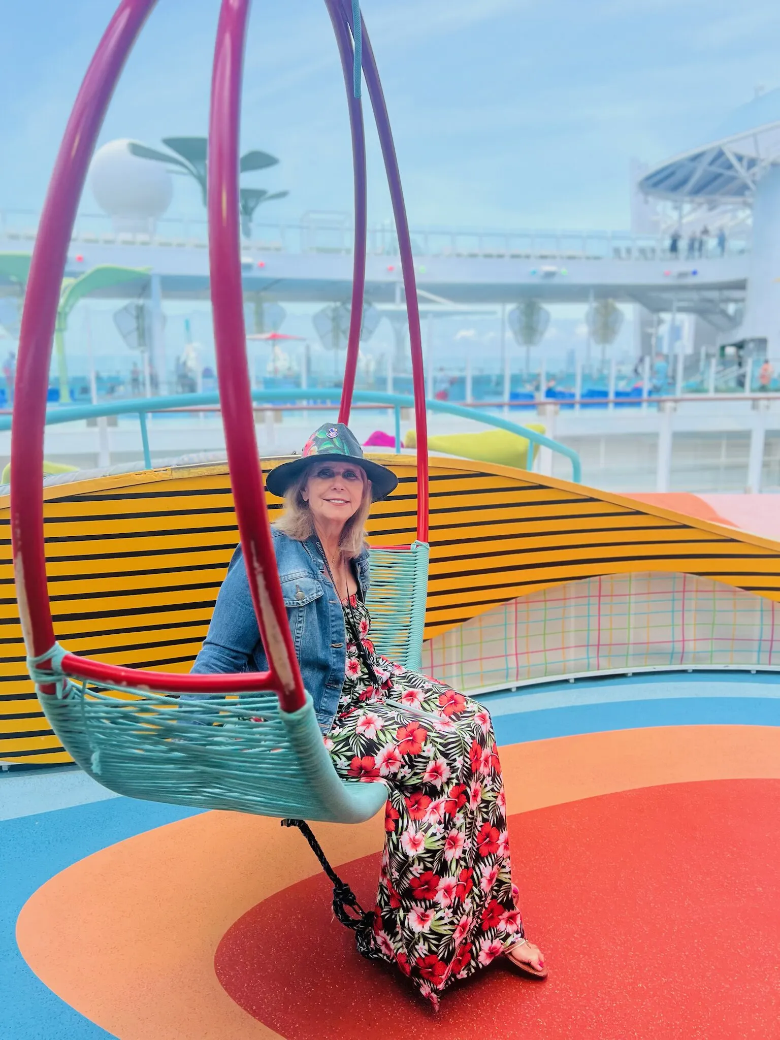 Jackpot Jill relaxes on a hanging swing chair on a colorful cruise ship deck.