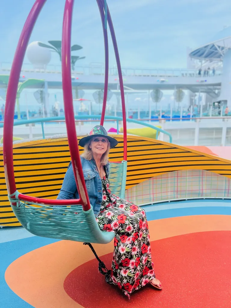 Jackpot Jill relaxes on a hanging swing chair on a colorful cruise ship deck.